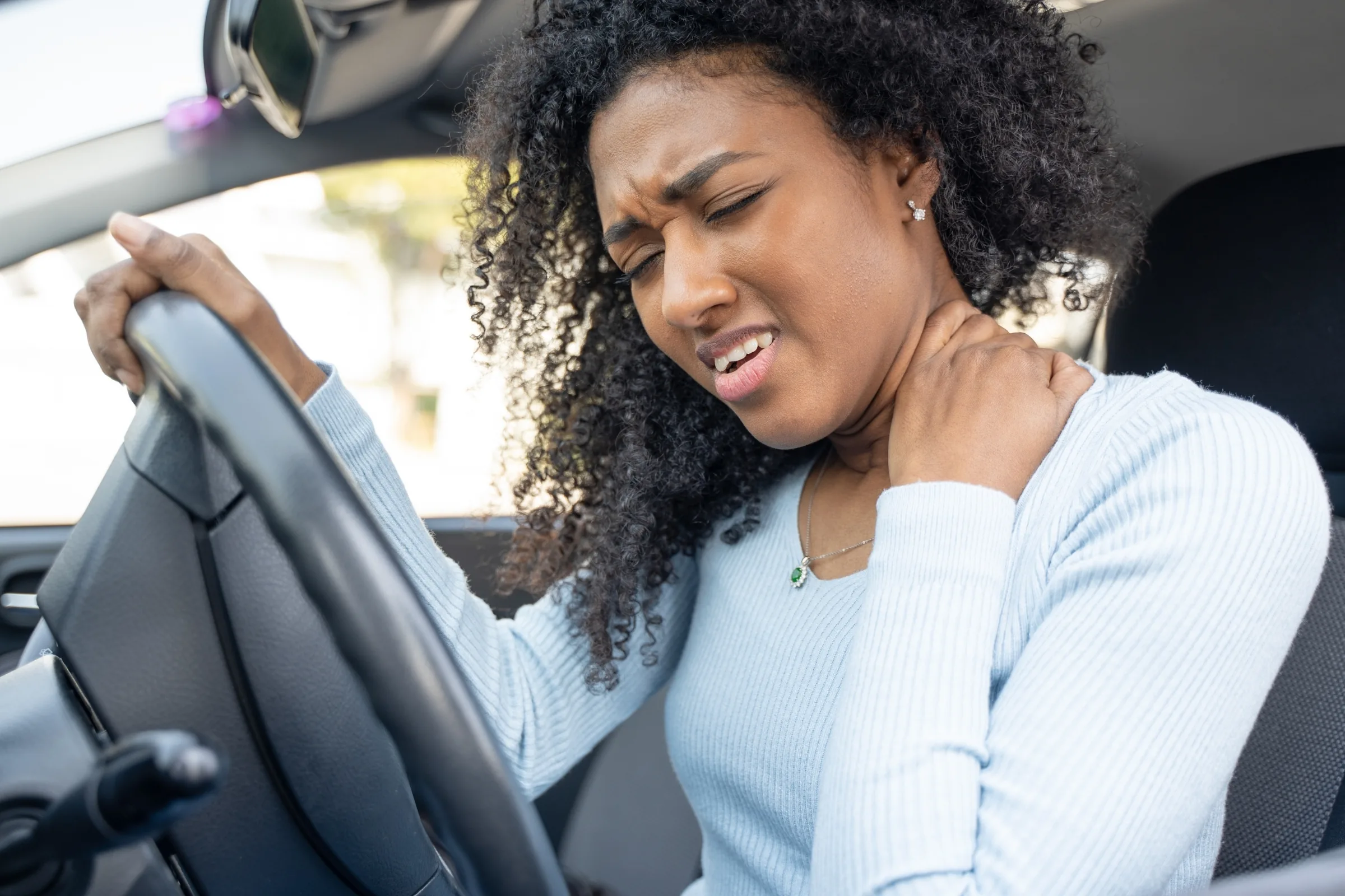 Woman in a car holding the side of her neck