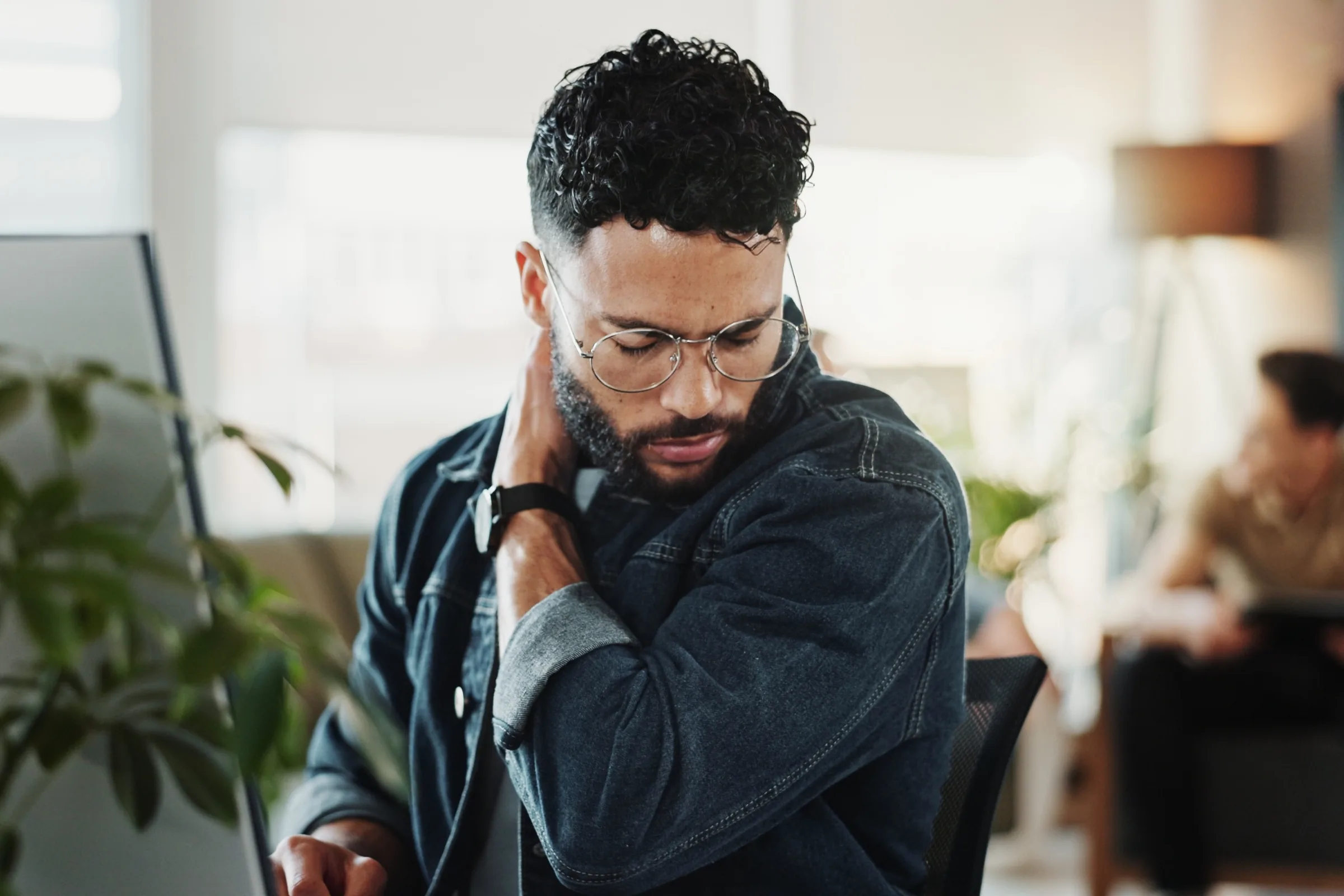 Man at a desk holding the back of his neck
