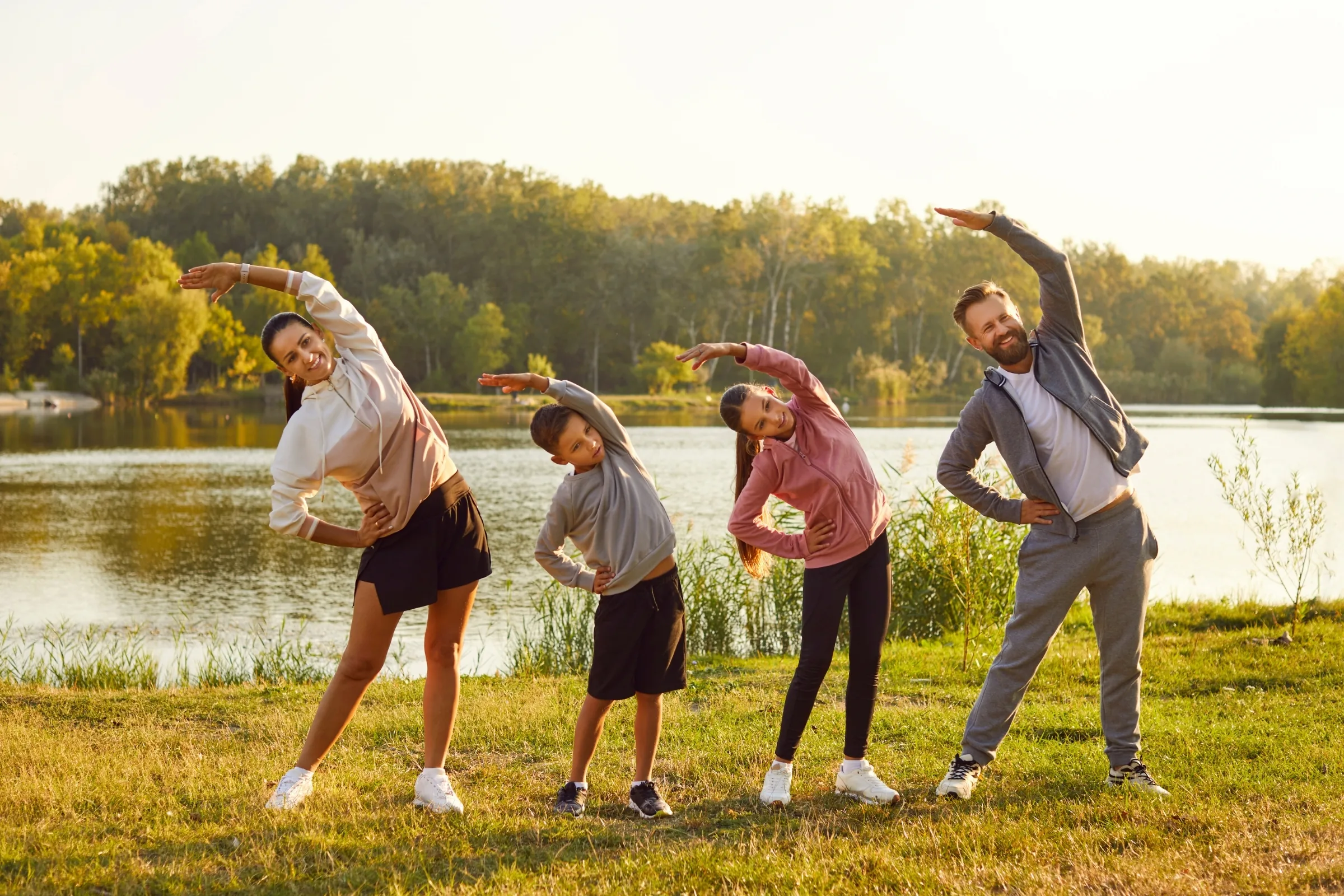 Family stretching on the grass beside a lake